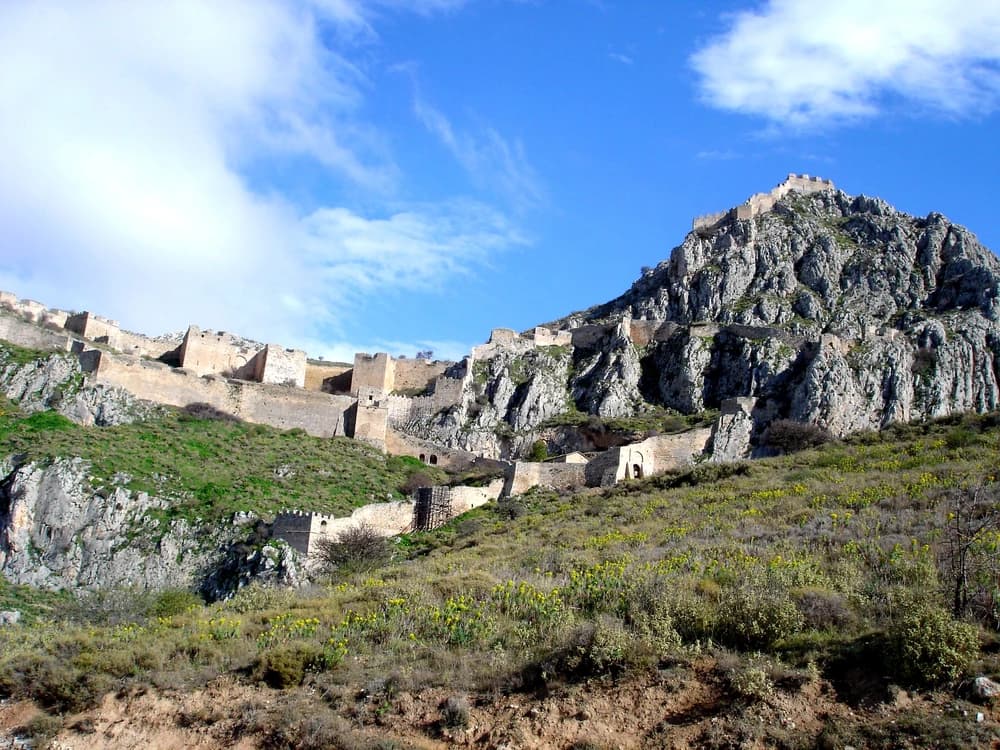 Acrocorinth's medieval walls crowning the 575-metre summit above the Corinthian plain, with the Gulf of Corinth visible beyond