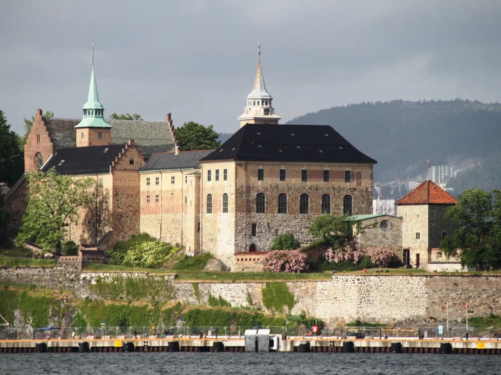 Akershus Fortress above the Oslofjord at dusk, its towers reflected in the water