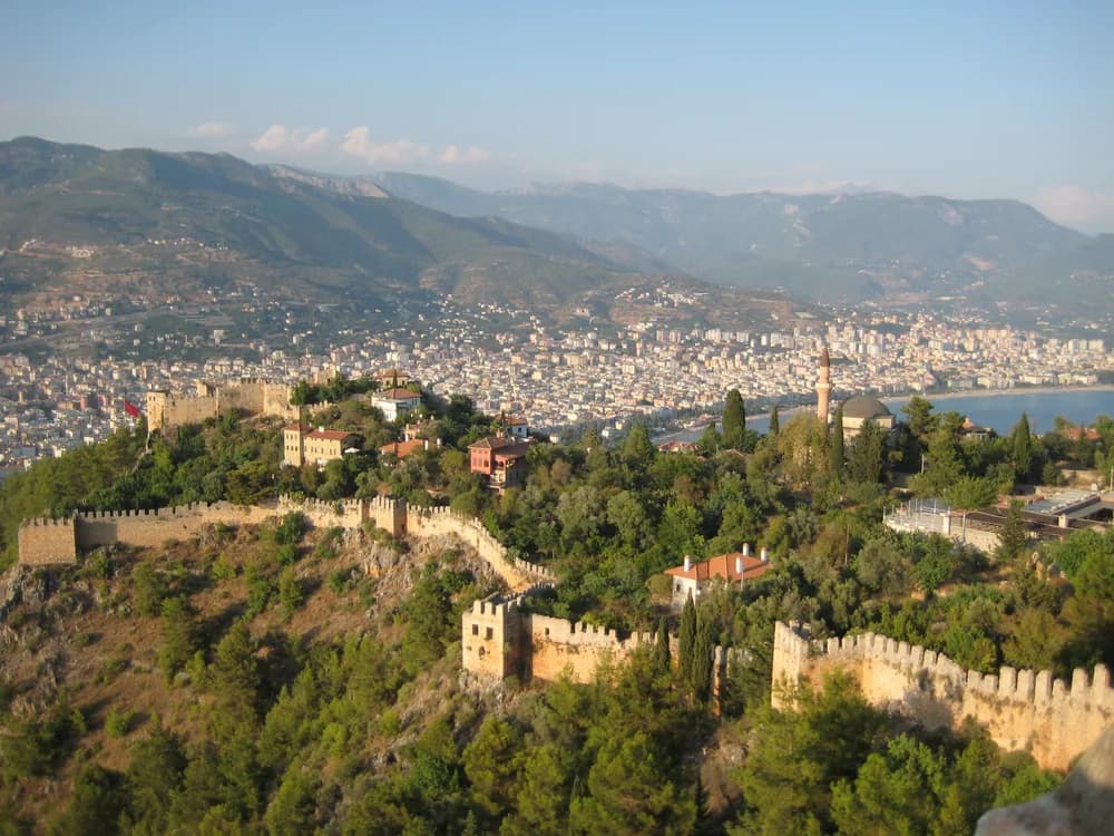 Alanya Castle's red sandstone walls and the Red Tower rising above the Turkish Riviera coastline