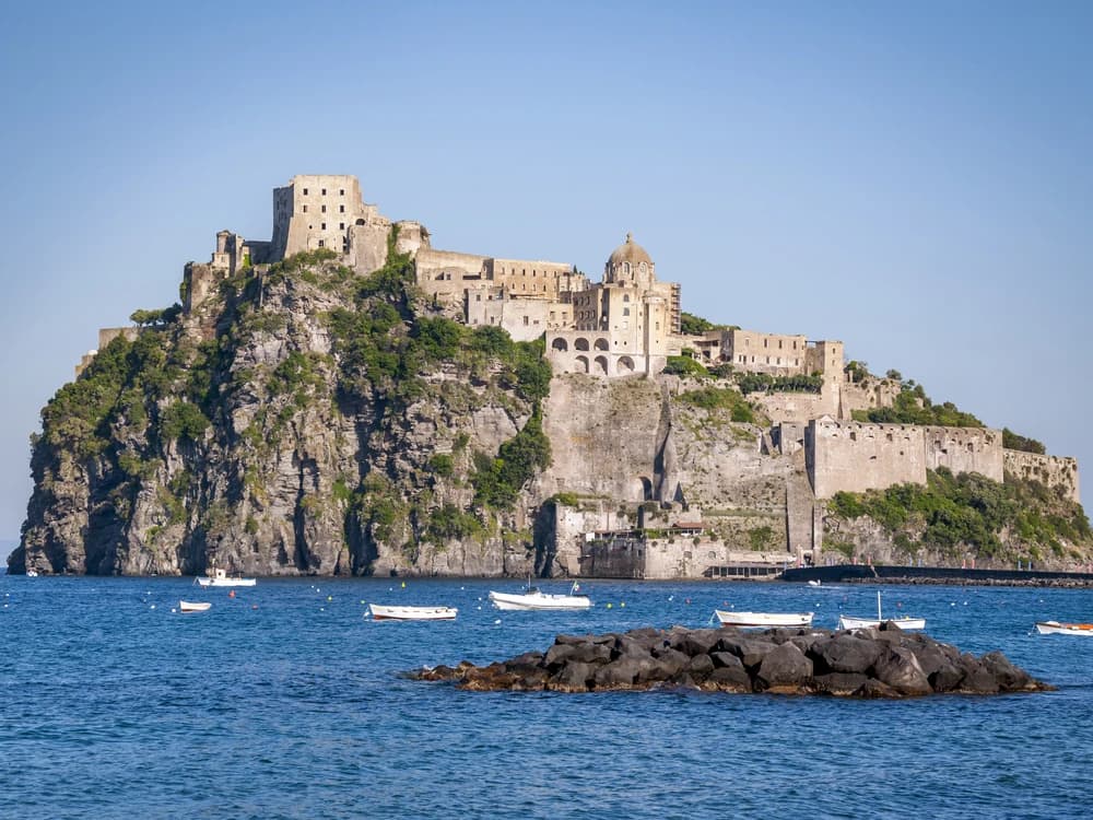 Castello Aragonese d'Ischia rising 113 metres from its volcanic islet above the blue Bay of Naples, with the causeway connecting it to the island of Ischia below