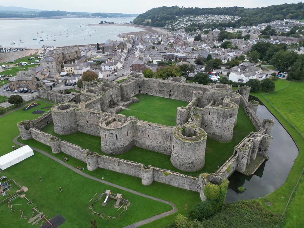 Beaumaris Castle's perfectly symmetrical concentric walls and towers reflected in the surrounding moat, Anglesey, Wales