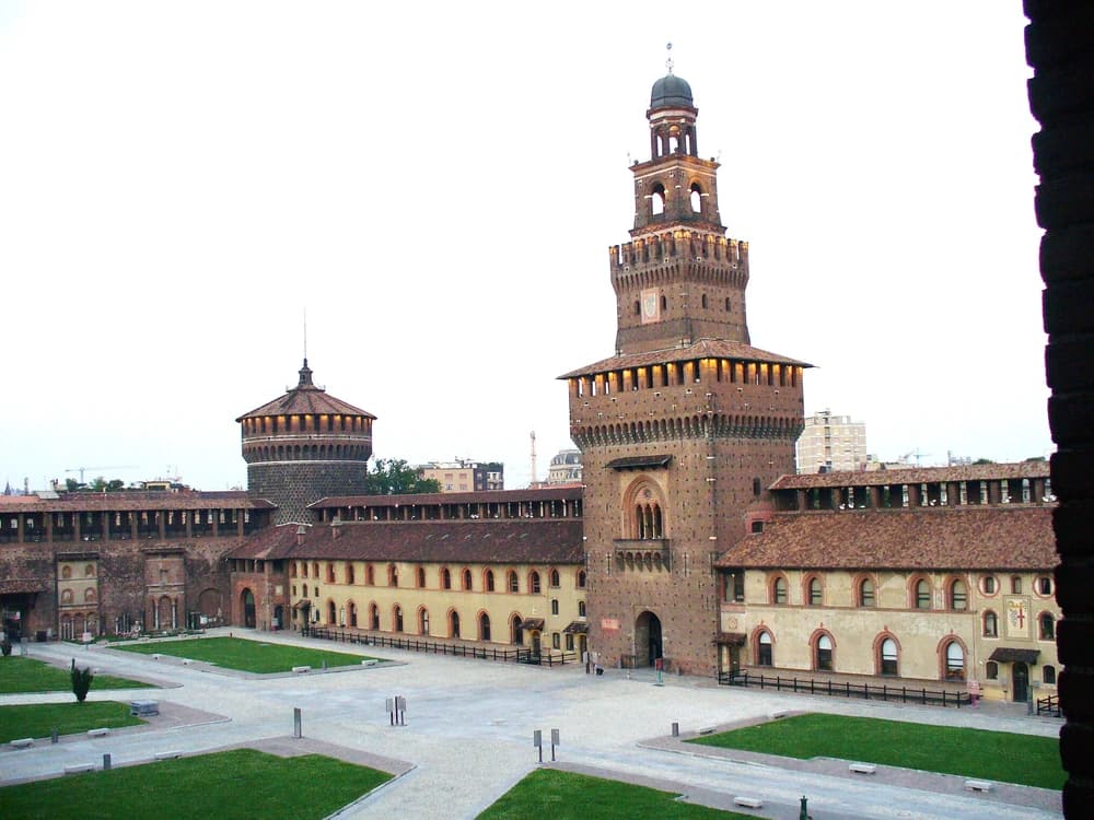 Castello Sforzesco's main Filarete Tower rising above the entrance piazza in central Milan, framed by the medieval red-brick walls of the fortress