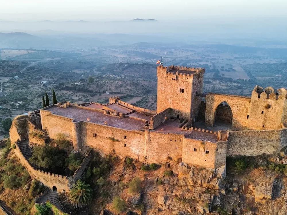 Castillo de Luna above Alburquerque in Extremadura — the 13th-century frontier fortress on the Spain-Portugal border with its rectangular keep and the medieval Villa Adentro within the outer walls