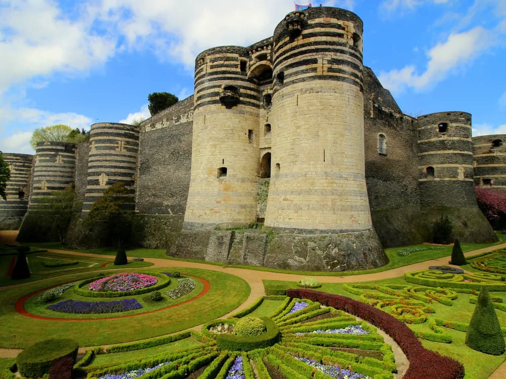 The striped black-and-white Angevin towers of Château d'Angers rising above their moat-side gardens