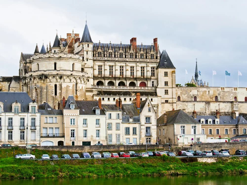 Château d'Amboise perched on its clifftop above the Loire river at sunset, towers and chapel silhouetted against the sky