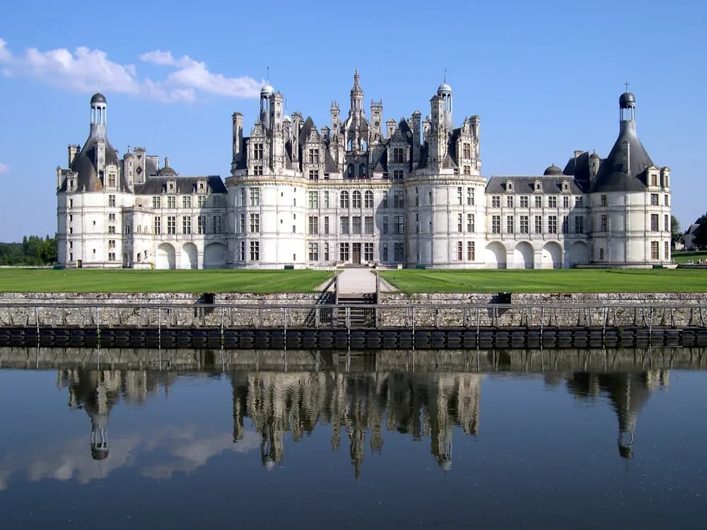 Château de Chambord reflected in the Cosson river, with its extraordinary roofline of towers and chimneys against a stormy sky