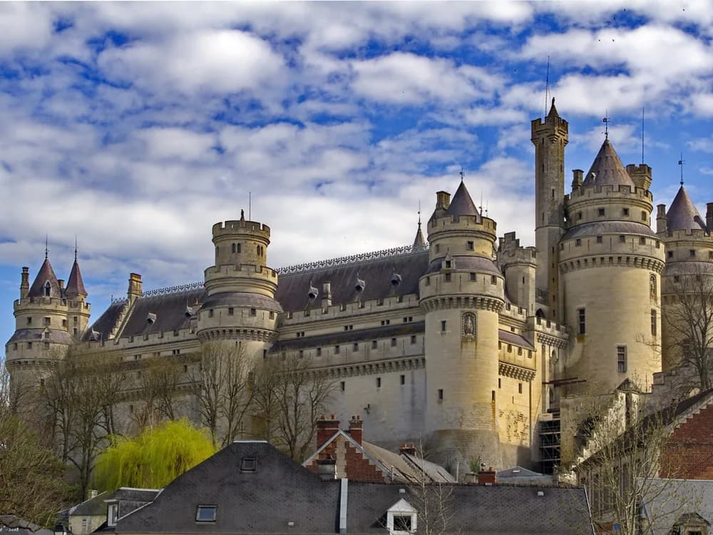 Château de Pierrefonds rising above the village, towers and ramparts reflected in the village lake
