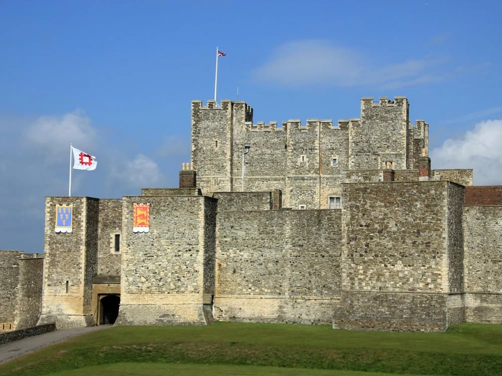 Dover Castle's massive Norman Great Tower rising above the white chalk cliffs of Kent, with the English Channel glinting silver in the distance