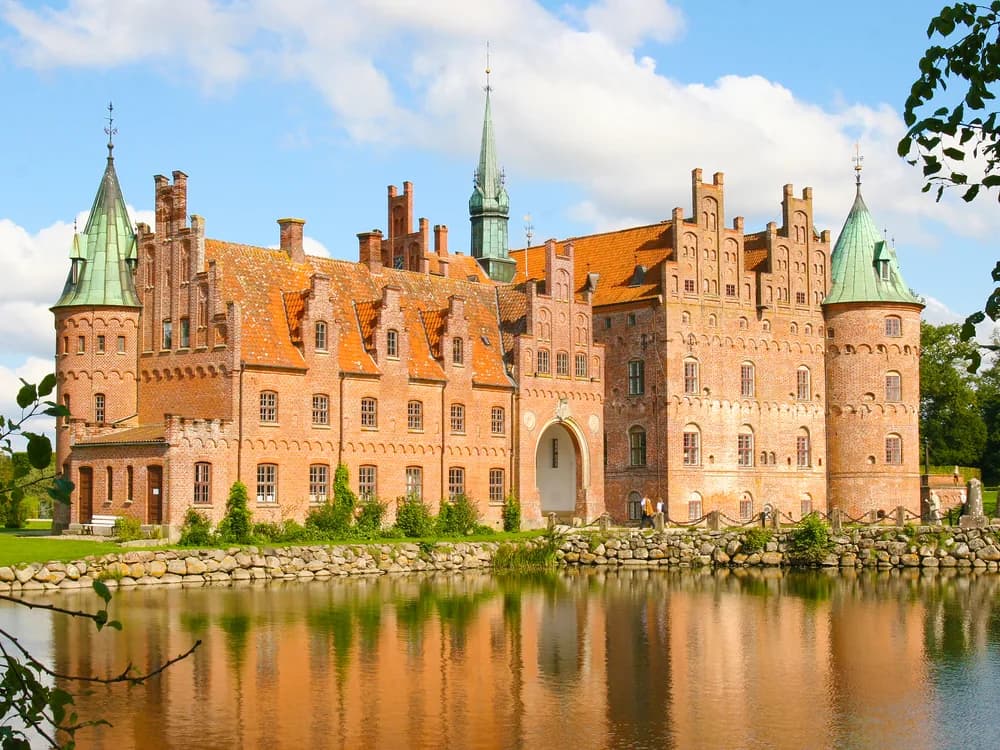 Egeskov Castle's Renaissance towers reflected in the surrounding moat on the island of Funen, Denmark