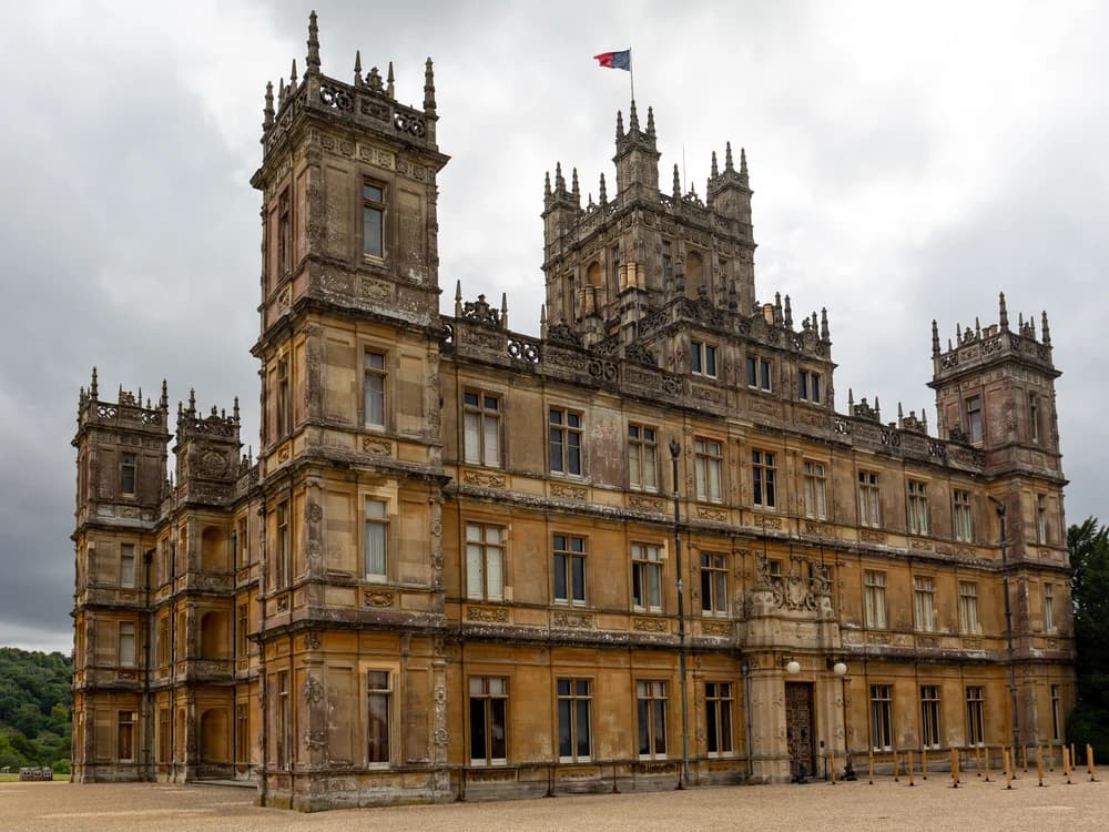 Highclere Castle's Victorian Gothic towers rising above landscaped lawns in Hampshire, instantly recognisable as the Downton Abbey country house