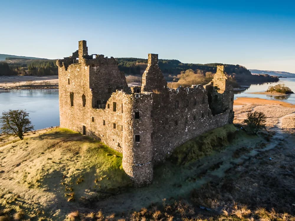 Kilchurn Castle on Loch Awe in Argyll, Scotland — the ruined Campbell tower house on its former island promontory, reflected in the still water of the loch with Ben Cruachan in the background