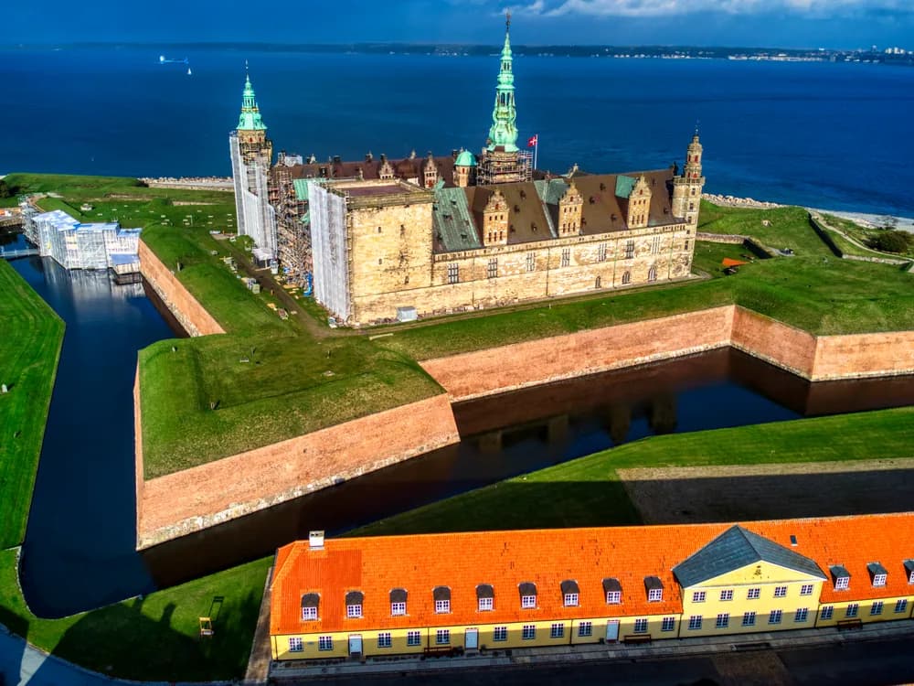 Kronborg Castle on its promontory above the Øresund strait at dawn, Sweden visible across the water