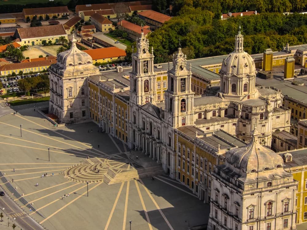 The colossal Baroque facade and twin bell towers of Mafra Palace in Portugal, stretching across the main square
