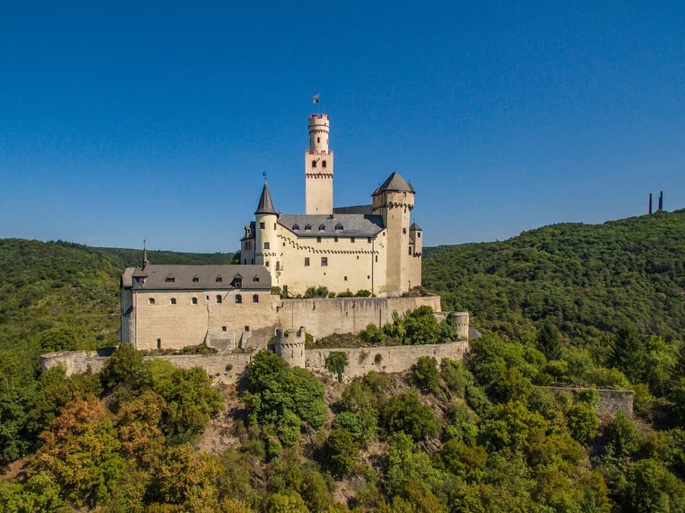 Marksburg Castle rising above the Rhine Gorge near Braubach, with the river and vine-covered slopes below
