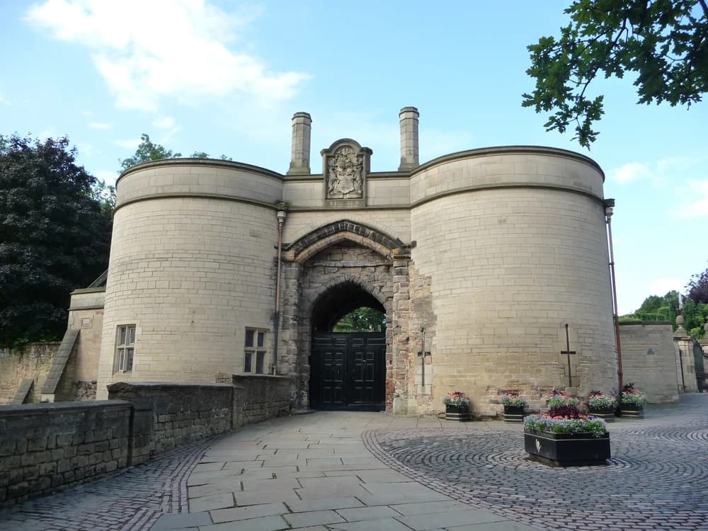 Nottingham Castle's baroque ducal mansion rising above Castle Rock, with the famous Robin Hood bronze statue standing guard at the gates below