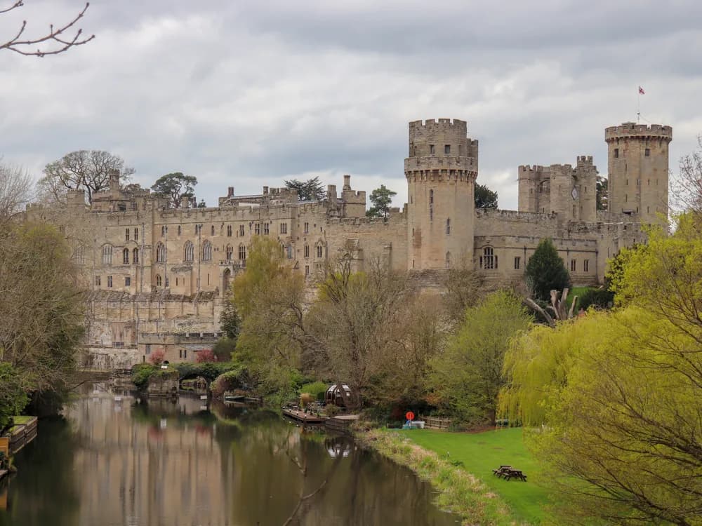 Warwick Castle rising above the River Avon with its medieval towers reflected in the water