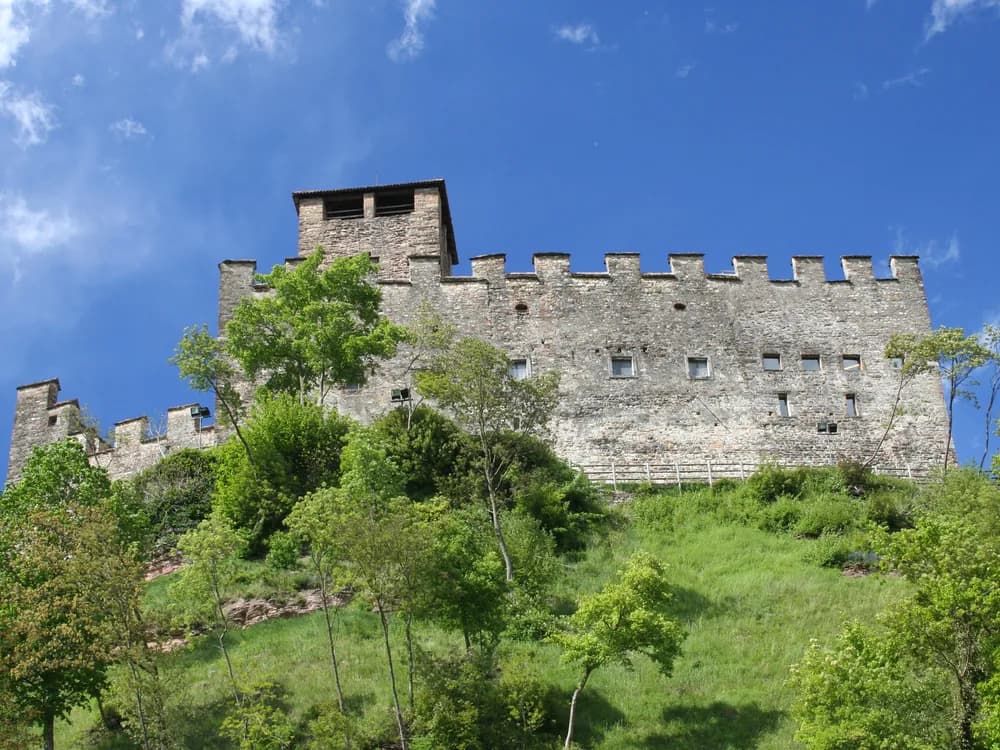 Zumelle Castle in the Valbelluna with the Dolomites rising behind — the medieval fortress at Mel near Belluno, with its restored interior rooms and the Medieval Tavern tasting experience