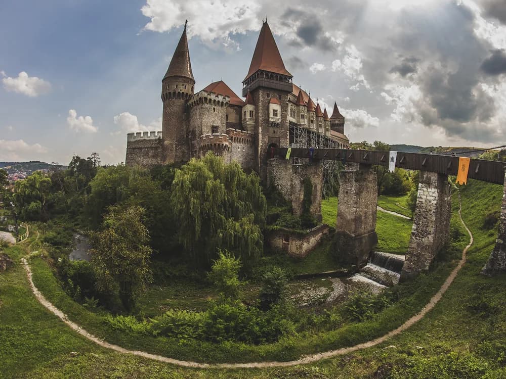 Corvin Castle's Gothic towers rising above the Zlasti river on a misty Transylvanian morning