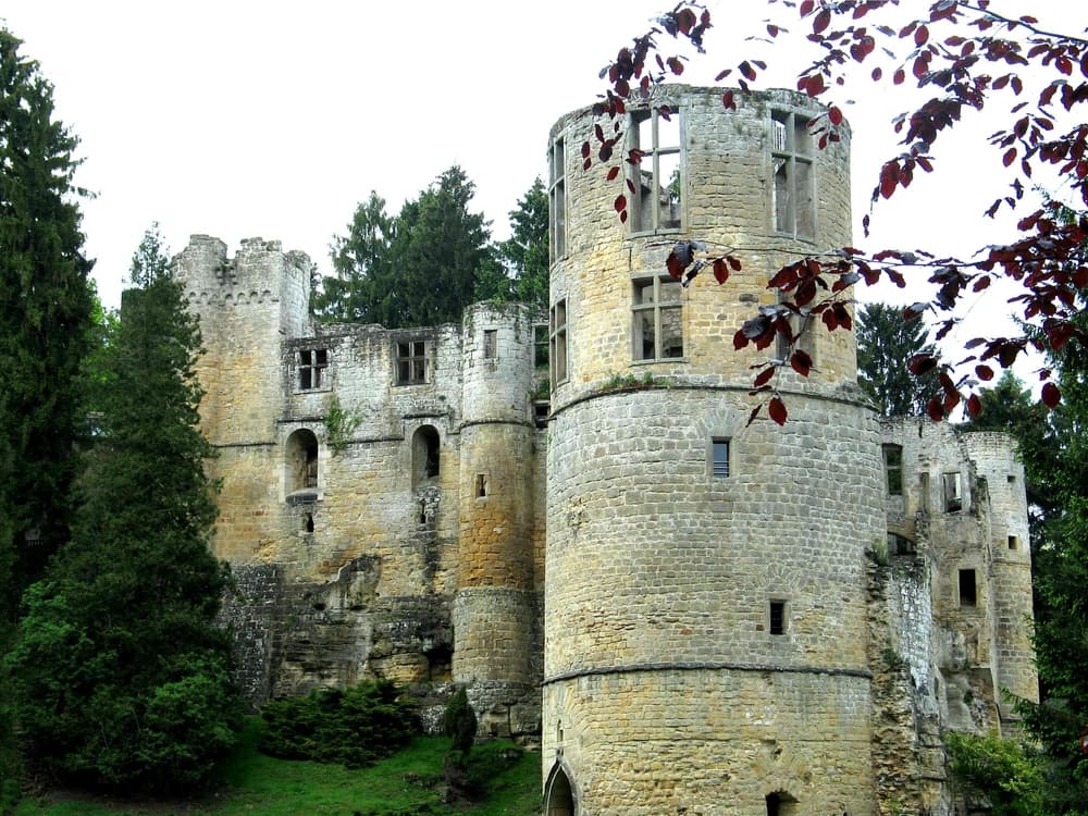 Beaufort Castle ruins at dusk in the Mullerthal forest, Luxembourg — ivy-covered towers and collapsed vaults, one of three castles visited on the Ghost Legends private tour
