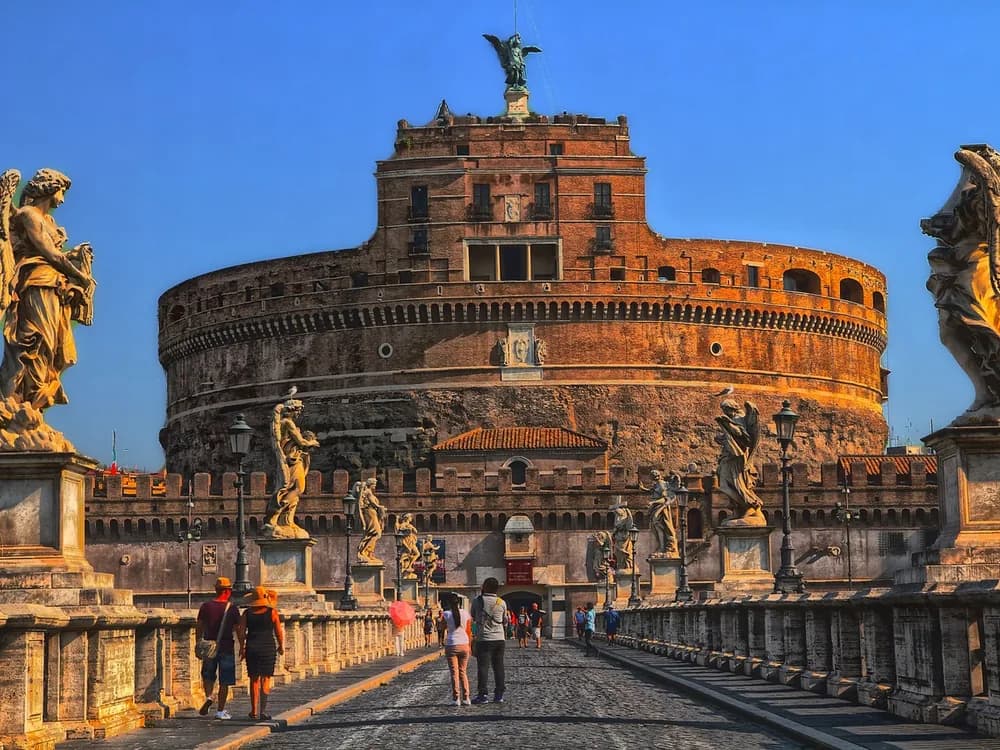 Castel Sant'Angelo at dusk reflected in the Tiber, with the Angel Bridge in the foreground