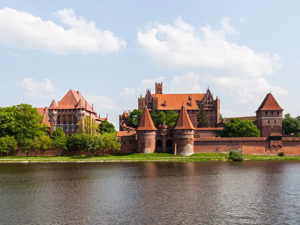Malbork Castle Gothic towers reflected in the Nogat River at sunset, Poland