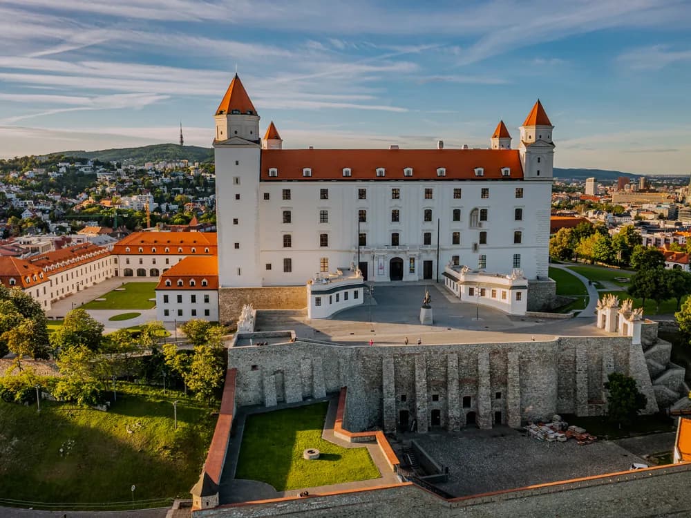 Bratislava Castle rising above the Danube — the four-towered white fortress nicknamed 'the upside-down table', rebuilt from a 140-year ruin and now housing the Slovak National Museum