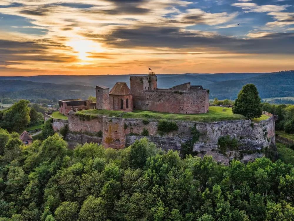 Château de Lichtenberg in the Vosges du Nord Regional Natural Park, Alsace — the 13th-century castle comprehensively redesigned for gunpowder artillery in 1580, with its warm red Vosges sandstone walls above the Alsatian forest