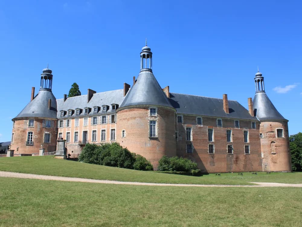 Château de Saint-Fargeau in the Puisaye, Burgundy — the five pink-brick towers of the 15th-century château at dusk, with the illuminations of the Spectacle de Saint-Fargeau visible