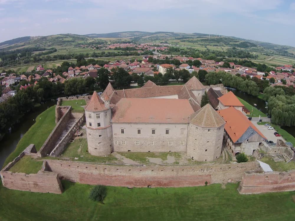 Făgăraș Fortress (Cetatea Făgărașului) in Transylvania, Romania — the best-preserved water-moated castle in Romania, with its continuously filled moat, corner bastions, and the Făgăraș Mountains in the background