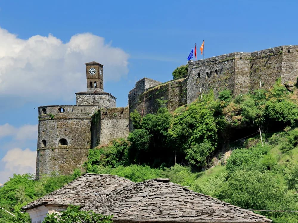 Gjirokastra Castle's towers rising above the UNESCO-listed old town of Gjirokastër, Albania — the 12th-century hilltop fortress expanded by Ali Pasha and later used as a communist political prison