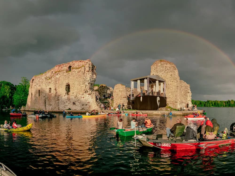 Koknese Castle (Kokneses pils) ruins on the Daugava River in Latvia — the 13th-century Bishop of Riga's fortress, partially flooded by the 1966 Pļaviņas hydroelectric reservoir, with medieval walls standing in still water