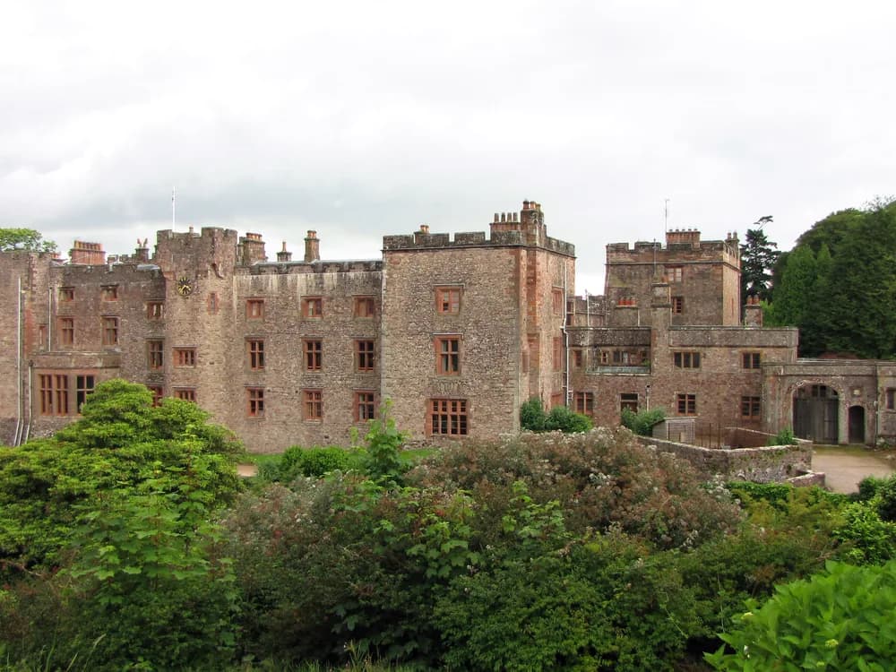 Muncaster Castle above the Esk valley in the western Lake District — the medieval peel tower and Victorian Gothic additions of the Pennington family's ancestral home, with 70 acres of Himalayan rhododendron gardens