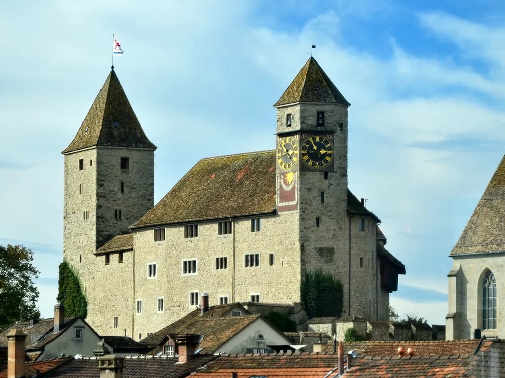Rapperswil Castle on its Lake Zurich promontory — the 13th-century Swiss castle above the Rose City's rose gardens, housing the Polish Museum Rapperswil since 1930, with the wooden bridge visible at the narrows