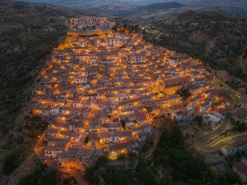 Rocca Imperiale Castle on its Ionian coast ridge in Calabria — Frederick II's 1225 Hohenstaufen hilltop fortress above the medieval village and PGI lemon groves, with the Ionian Sea beyond