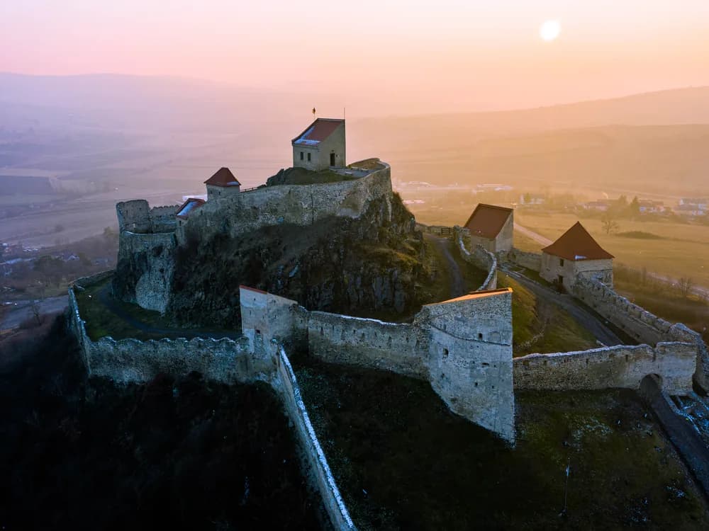 Rupea Fortress (Cetatea Rupea) on its basalt rock above the Olt valley in Brașov County, Transylvania, Romania — the three levels of the medieval Saxon refuge fortress restored by a 2010–2013 EU-funded project