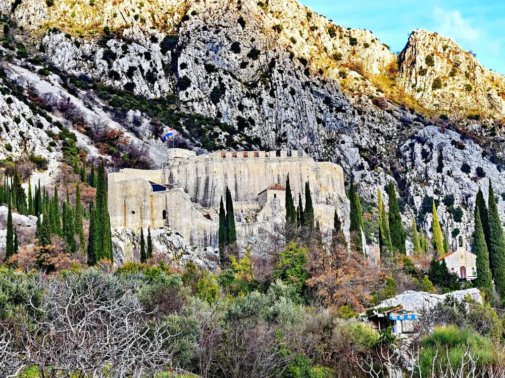 Sokol Fortress (Sokol Grad) on a karst cliff above the Konavle Valley near Dubrovnik, Croatia — the medieval Ragusan fortress whose name means 'falcon,' overlooking the agricultural valley that was one of the Dubrovnik Republic's most valued territories