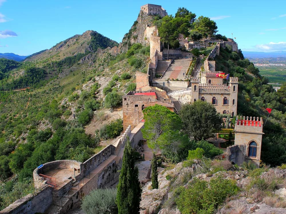 Xàtiva Castle's twin fortifications on the limestone ridge above the town of Xàtiva, Valencia, with the plain stretching toward the Mediterranean below
