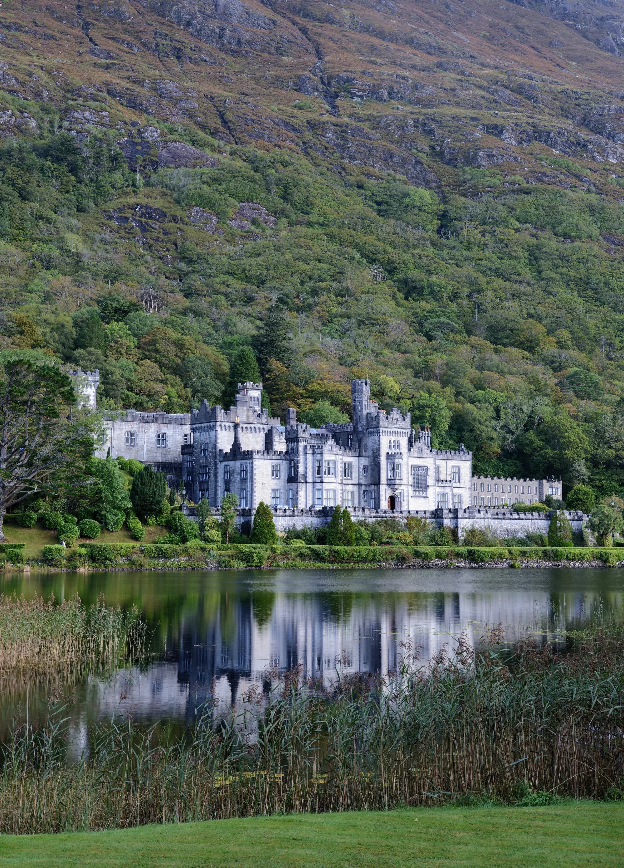 Kylemore Abbey reflected in the still waters of Kylemore Lough, Connemara, with the Twelve Bens mountains behind the neo-Gothic Victorian castle