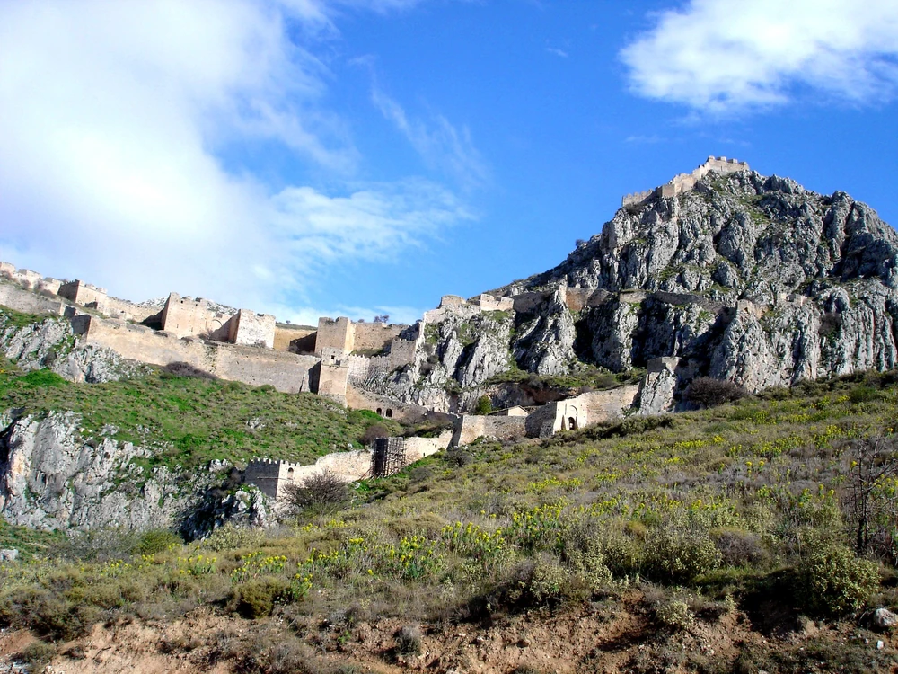 Acrocorinth's medieval walls crowning the 575-metre summit above the Corinthian plain, with the Gulf of Corinth visible beyond