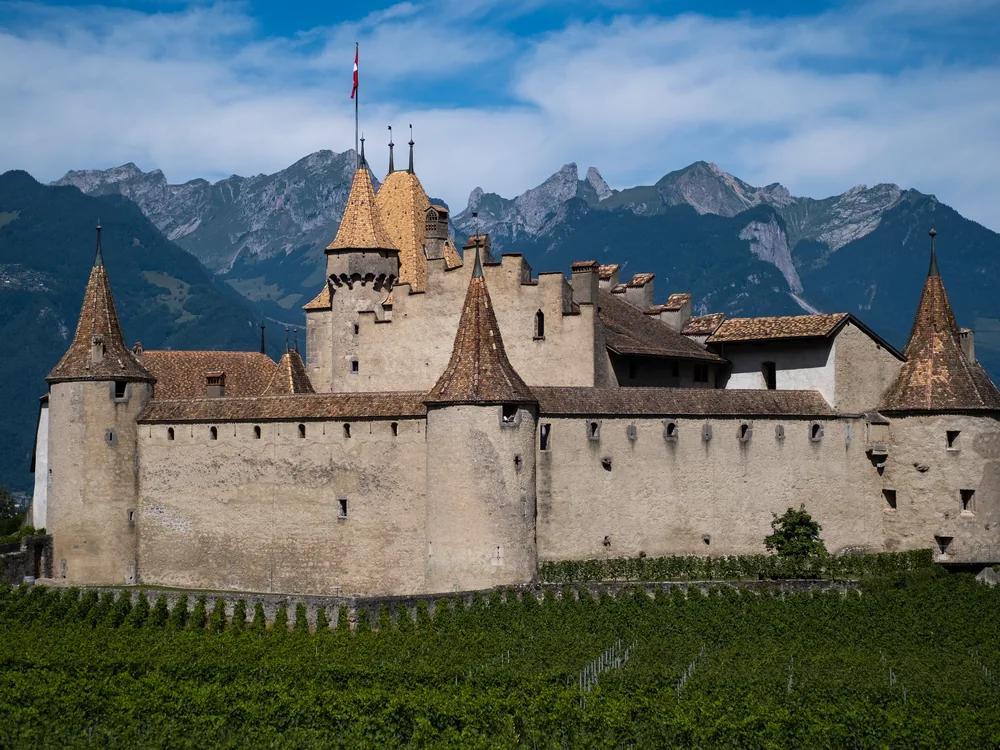 Aigle Castle surrounded by the Chasselas vineyards of the Chablais — the 13th-century Bernese Gothic fortress at the mouth of the Rhône Valley, home to the Vine and Wine Museum
