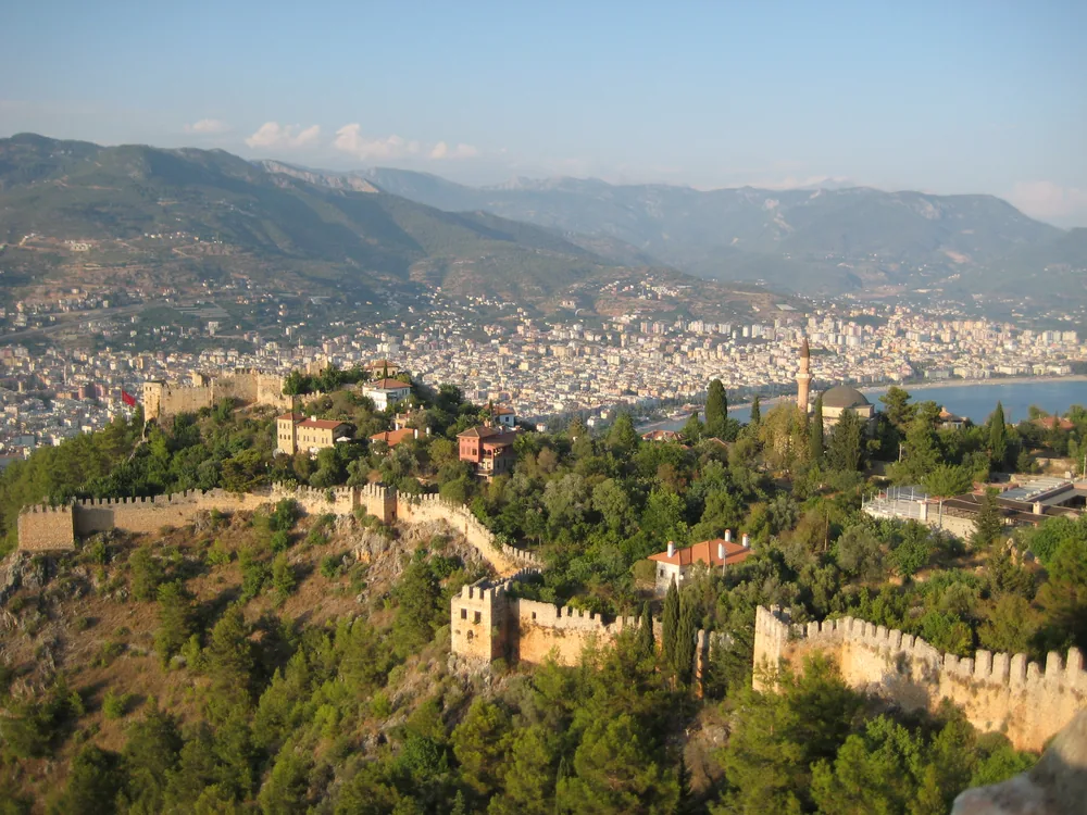 Alanya Castle's red sandstone walls and the Red Tower rising above the Turkish Riviera coastline