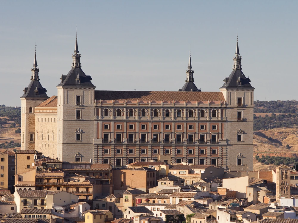 The Alcázar of Toledo seen from across the Tagus River gorge, its four Renaissance towers rising above the medieval rooftops of the city