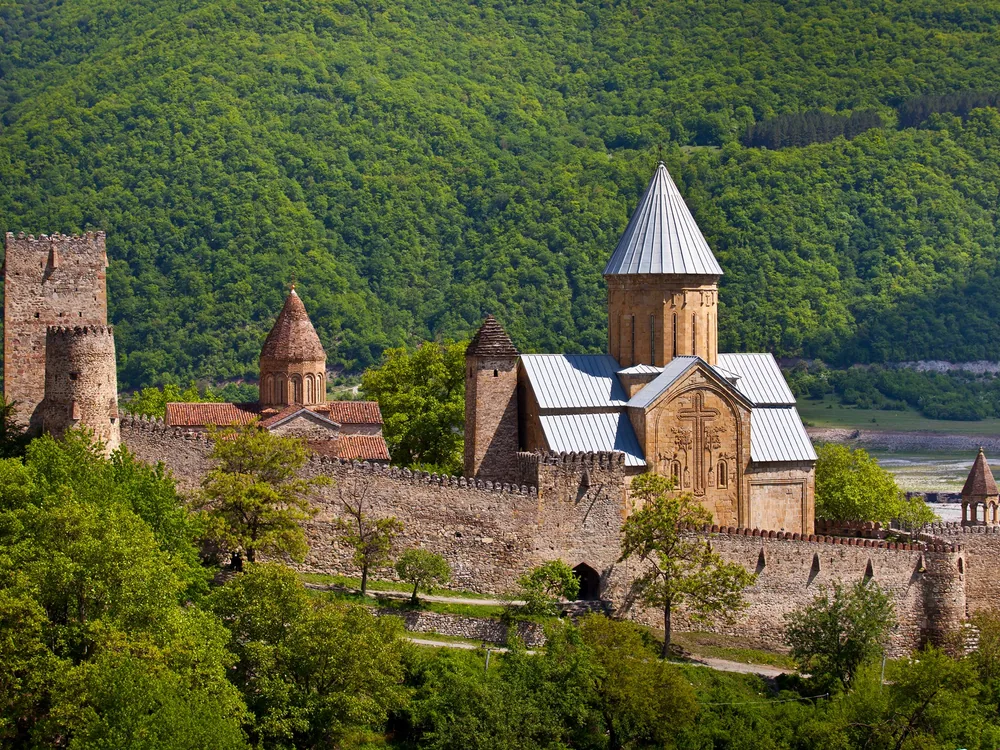 Ananuri Fortress medieval towers and churches reflected in the turquoise Zhinvali Reservoir in the Caucasus mountains of Georgia