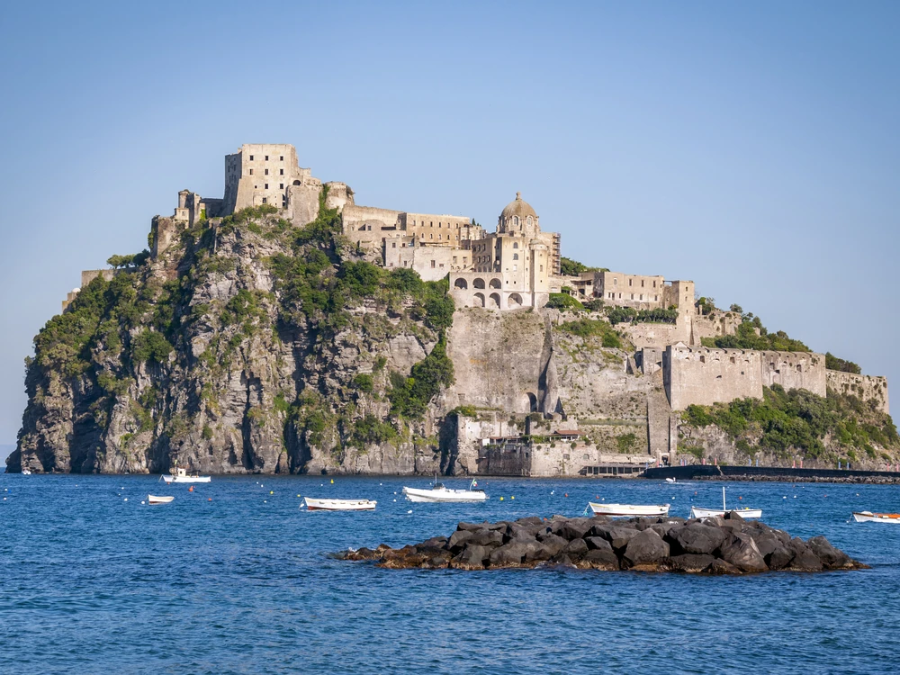 Castello Aragonese d'Ischia rising 113 metres from its volcanic islet above the blue Bay of Naples, with the causeway connecting it to the island of Ischia below