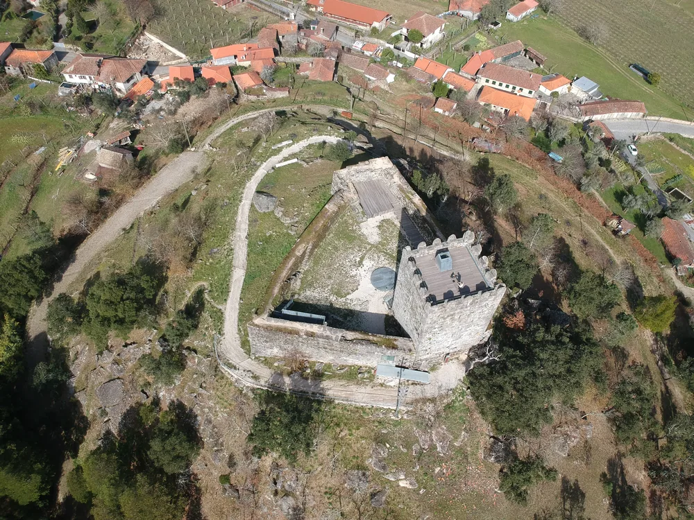 Arnóia Castle ruins on a granite hilltop above the Tâmega valley in Celorico de Basto, northern Portugal — the 17-metre Romanesque keep and defensive tower of a 10th-century frontier castle