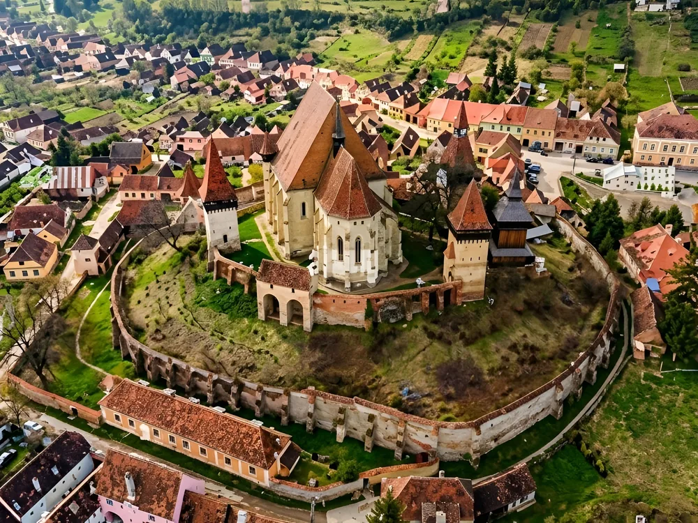Biertan Fortified Church (Birthälm) in Sibiu County, Transylvania, Romania — the UNESCO-listed triple-walled Saxon fortified church on its hilltop, with three concentric rings of defensive walls and the Gothic spire above