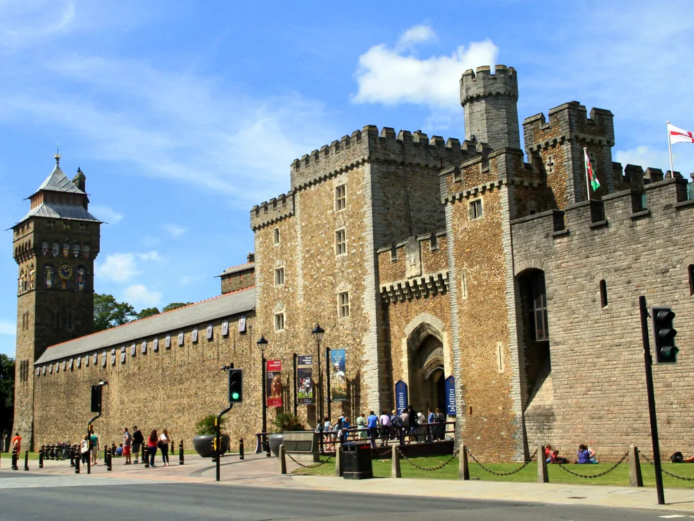 Cardiff Castle (Castell Caerdydd) in the centre of the Welsh capital — the Norman shell keep on its Roman mound behind the outer wall, with the Victorian Clock Tower of the Bute/Burges Gothic Revival apartments