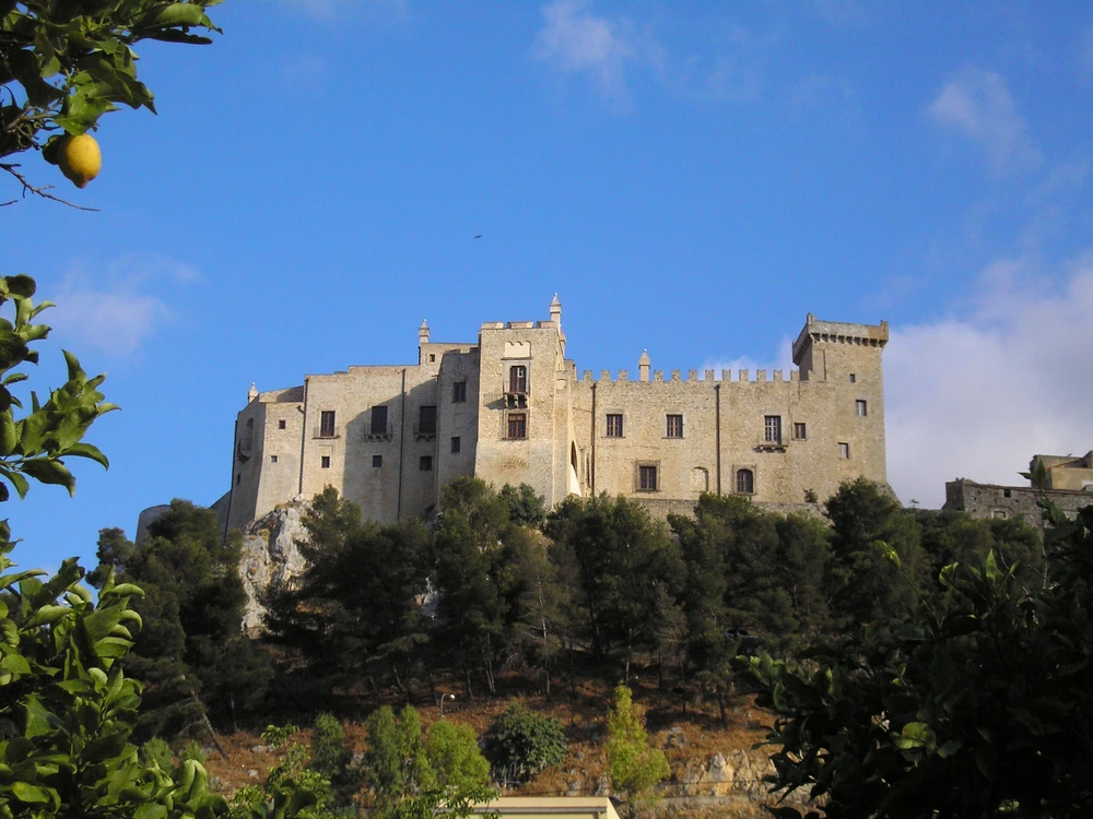 Carini Castle's Norman towers and curtain walls on the hilltop above the town of Carini, Sicily, with the Conca d'Oro plain visible below