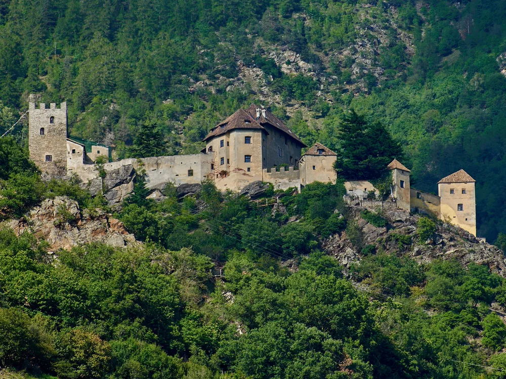 Castel Juval on its hilltop above the Vinschgau valley in South Tyrol, surrounded by apple orchards and with the Alps rising behind