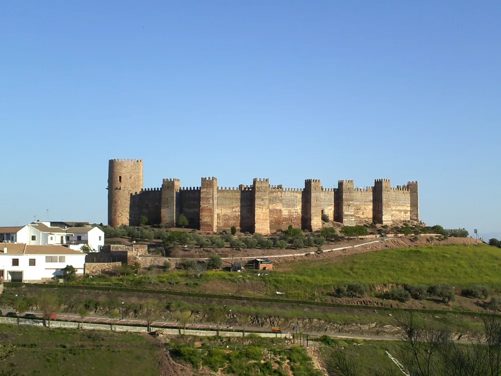 The semicircular towers and curtain wall of Baños de la Encina Castle above the olive groves of Jaén province
